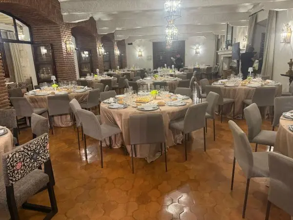 Salón de eventos con mesas redondas preparadas para un servicio de cena o comida de empresa.