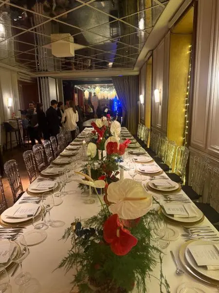 Mesa imperial larga decorada con centros florales rojos y blancos para un evento de gala.