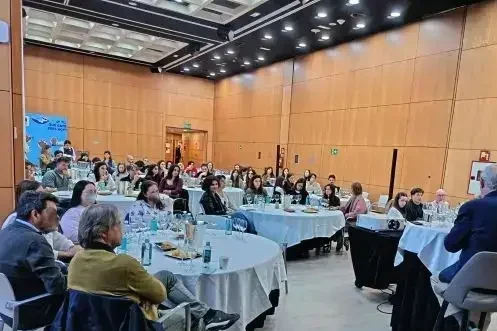 Evento corporativo en montaje tipo banquete con mesas redondas orientadas a ponente en sala de conferencias